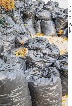 Pile of black plastic trash bags with debris in outdoor setting Pile of black plastic trash bags with debris in outdoor setting 143018726