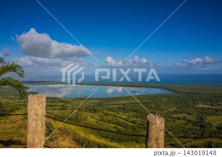 Coastal lagoon with green hills under blue sky and white clouds Coastal lagoon with green hills under blue sky and white clouds 143019148