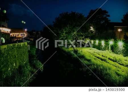 Night park scene with canal and illuminated grass paths 143019300