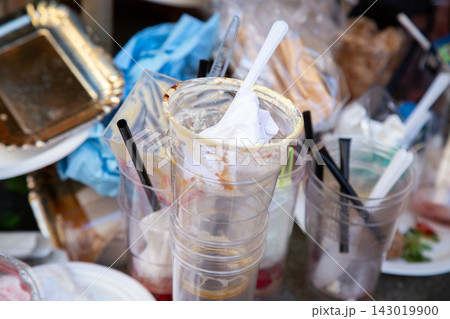 Discarded plastic drink cups with straws, napkins, and leftover beverage residue piled together in messy close up, suggesting post event cleanup, waste, and recycling challenges in casual food service Discarded plastic drink cups with straws, napkins, and leftover beverage residue piled together in messy close up, suggesting post event cleanup, waste, and recycling challenges in casual food service 143019900
