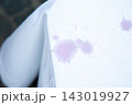 Close up of white fabric with purple stains and speckled marks, showing soft textile texture, uneven dye spots, and abstract surface detail with strong light and shallow focus 143019927