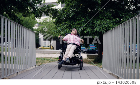 Person with spina bifida driving electric wheelchair on ramp Person with spina bifida driving electric wheelchair on ramp 143020308