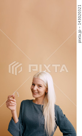 Woman smiling holding clear dental aligner Woman smiling holding clear dental aligner 143020321