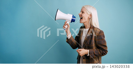 Mature woman shouting announcement using megaphone Mature woman shouting announcement using megaphone 143020338