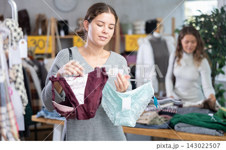 Young woman chooses panties in clothing store Young woman chooses panties in clothing store 143022507