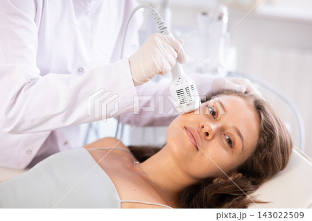Young girl undergoing cosmetic facial treatment using cold hammer Young girl undergoing cosmetic facial treatment using cold hammer 143022509