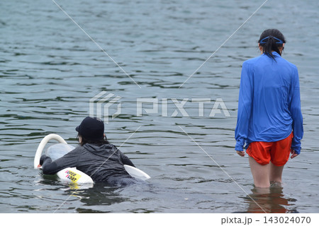 水着姿でバックパックを背負った男性と少女が、湾の海を泳いでいる。 水着姿でバックパックを背負った男性と少女が、湾の海を泳いでいる。 143024070