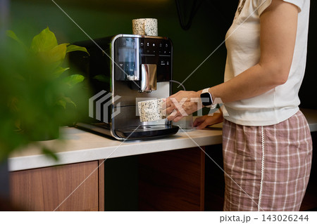 Woman making coffee with automatic coffee machine at home Woman making coffee with automatic coffee machine at home 143026244