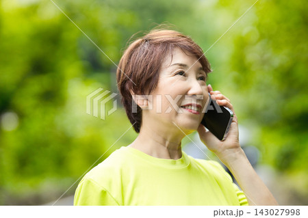 スマホで通話するスポーツウェアのシニア女性 スマホで通話するスポーツウェアのシニア女性 143027998