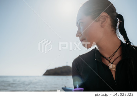Woman Beach Ocean View - Young woman in black shirt with ponytail looks out at ocean and island on a sunny day. Woman Beach Ocean View - Young woman in black shirt with ponytail looks out at ocean and island on a sunny day. 143028322
