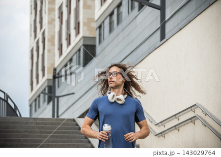 Male runner holding water bottle after outdoor workout 143029764