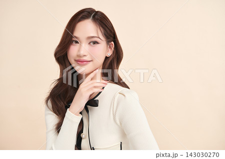 A beautiful young Asian woman with clean, fresh skin against a beige background. Skincare, facial treatment, cosmetology, beauty, and spa. An elegant portrait of an Asian woman. A beautiful young Asian woman with clean, fresh skin against a beige background. Skincare, facial treatment, cosmetology, beauty, and spa. An elegant portrait of an Asian woman. 143030270