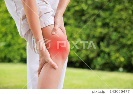 Close up of person bending and holding bare knee with red highlighted area indicating severe joint pain, arthritis, muscle ache or sports injury. Healthcare, medical, and physical therapy concept. Close up of person bending and holding bare knee with red highlighted area indicating severe joint pain, arthritis, muscle ache or sports injury. Healthcare, medical, and physical therapy concept. 143030477