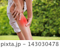 Close up of person holding bare calf muscle with red highlighted area indicating severe leg pain, muscle cramp, strain, or sports injury. Healthcare, physical therapy, and medical concept outdoors. 143030478