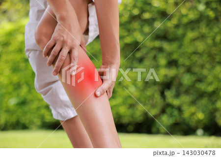 Close up of person holding bare calf muscle with red highlighted area indicating severe leg pain, muscle cramp, strain, or sports injury. Healthcare, physical therapy, and medical concept outdoors. 143030478