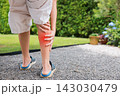 Close up of person standing holding bare calf with red highlighted area indicating severe leg pain, muscle cramp, strain, or sports injury. Healthcare, physical therapy, and medical concept outdoors. 143030479