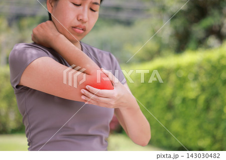 Close up unhappy Asian woman touching her elbow with a red highlighted area indicating severe joint pain, arthritis, muscle ache or sports injury. Healthcare, physical therapy, and medical concept. Close up unhappy Asian woman touching her elbow with a red highlighted area indicating severe joint pain, arthritis, muscle ache or sports injury. Healthcare, physical therapy, and medical concept. 143030482