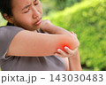 Stressed young Asian woman holding her elbow with red highlighted area indicating severe joint pain, arthritis, muscle sprain or sports injury. Healthcare, physical therapy, and medical care concept. 143030483