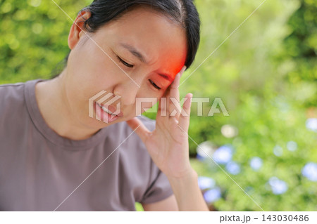 Unhappy Asian woman sitting on chair touching her head with red highlighted area indicating severe headache, migraine or brain pain. Concept of stress, sickness, healthcare, tension and mental health. Unhappy Asian woman sitting on chair touching her head with red highlighted area indicating severe headache, migraine or brain pain. Concept of stress, sickness, healthcare, tension and mental health. 143030486