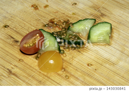 Left over salad from dinner chopped cucumber tomato onion food waste on chopping board Left over salad from dinner chopped cucumber tomato onion food waste on chopping board 143030841