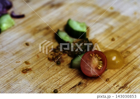 Left over salad from dinner chopped cucumber tomato onion food waste on chopping board 143030853