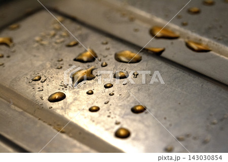 Drops of cooking fat oil liquid spilt on a stainless steel kitchen sink messy food preparation 143030854
