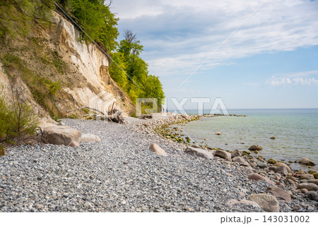 Famous white chalk cliffs and rocky Baltic Sea coastline in Jasmund National Park on Rugen island, Germany. Iconic natural landmark and coastal travel destination concept. Famous white chalk cliffs and rocky Baltic Sea coastline in Jasmund National Park on Rugen island, Germany. Iconic natural landmark and coastal travel destination concept. 143031002
