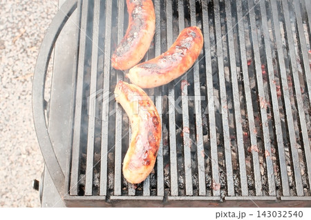 Sausages cooking on hot barbecue grill grates outdoors during the daytime 143032540