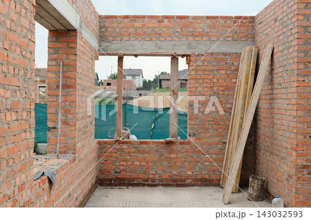Unfinished red brick wall structure under construction in a suburban area 143032593