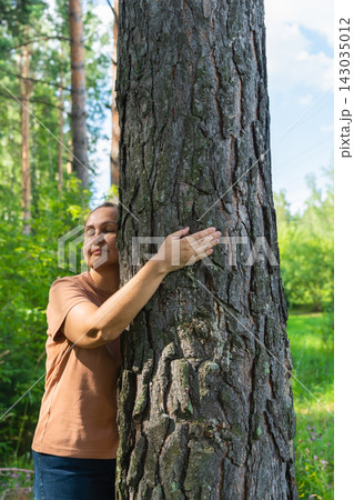 Mature caucasian female embracing tree in lush forest setting. Mental health, female harmony 143035012