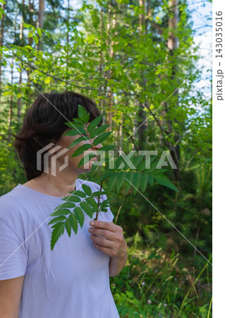 Caucasian female enjoying nature in forest holding fern leaf Caucasian female enjoying nature in forest holding fern leaf 143035016