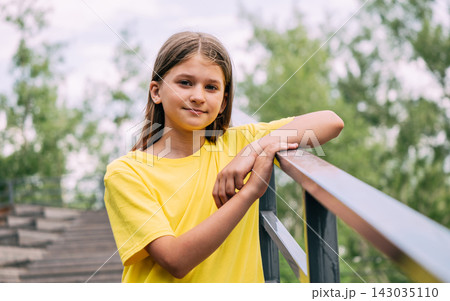 Portrait of a blonde girl in a bright yellow T-shirt against the background of the park 143035110