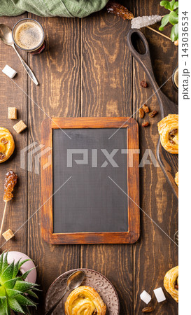 Rustic wooden table with empty chalkboard surrounded by pastries and coffee for mock up design Rustic wooden table with empty chalkboard surrounded by pastries and coffee for mock up design 143036534