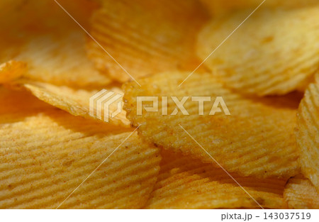 Commercial food photography of a macro background of crispy ridged potato chips with golden texture Commercial food photography of a macro background of crispy ridged potato chips with golden texture 143037519