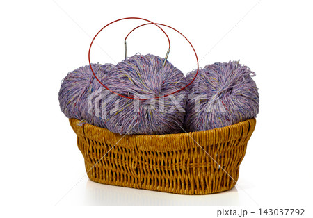 Wicker basket filled with balls of tweed yarn and circular knitting needles 143037792