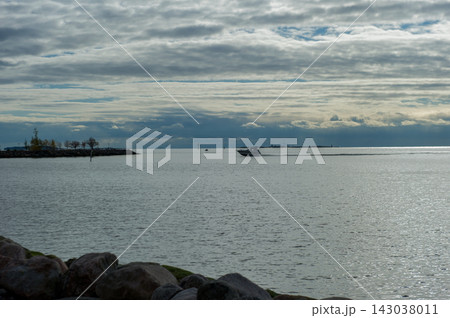 Commercial stock photo of a motorized boat cruising on a calm sea under a cloudy sky Commercial stock photo of a motorized boat cruising on a calm sea under a cloudy sky 143038011