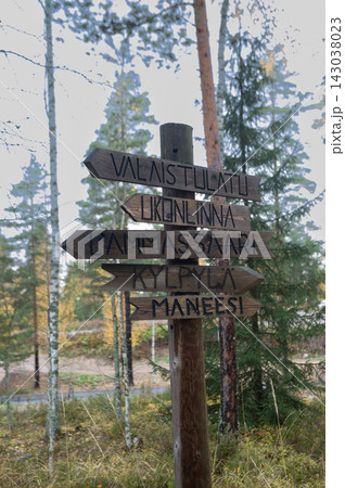 Wooden trail signpost with directional arrows in a forest 143038023