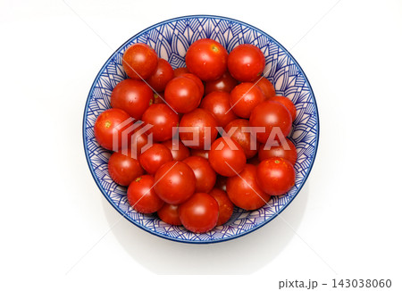 Top-down studio shot of a blue and white patterned bowl filled with cherry tomatoes on a white background Top-down studio shot of a blue and white patterned bowl filled with cherry tomatoes on a white background 143038060