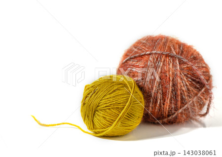 Two yarn balls in rust orange and chartreuse green with loose thread on white background Two yarn balls in rust orange and chartreuse green with loose thread on white background 143038061