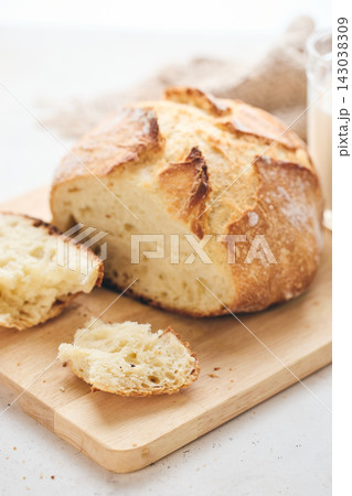 Sliced artisan sourdough bread with airy crumb on wooden board, glass of milk, and knitted cloth. Ideal for culinary, baking, and food photography projects. Sliced artisan sourdough bread with airy crumb on wooden board, glass of milk, and knitted cloth. Ideal for culinary, baking, and food photography projects. 143038309