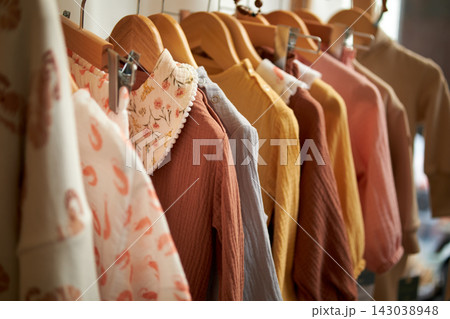Women's clothing on hangers made of natural fabrics, calm pastel colors in an eco-friendly and retro style. 143038948