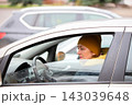 Woman sitting in car with yellow hat while parked in busy area during daytime 143039648