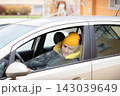 Woman sits inside a car wearing a yellow beanie while looking out of the window on a cold day 143039649