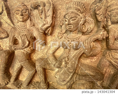 An ancient stone relief depicting Hindu deities. A detailed sculpture depicting Shiva with a third eye and Parvati seated nearby. 143041304