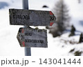 Weathered wooden directional signs on a mountain trail post pointing to Pralongia and Armentarola in the snowy Dolomites. Alpine Trail Signpost in Winter Snow Dolomites Italy 143041444