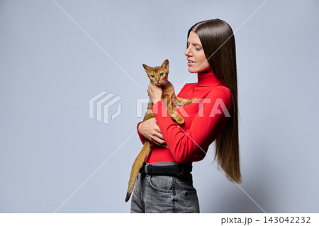 Smiling woman holding Abyssinian cat profile isolated on light gray background Smiling woman holding Abyssinian cat profile isolated on light gray background 143042232
