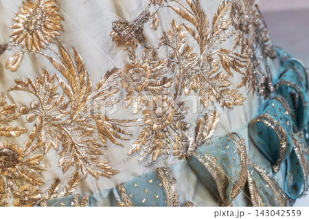 Ornate gold floral embroidery decorates vintage silk fabric Ornate gold floral embroidery decorates vintage silk fabric 143042559