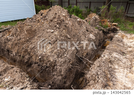 Backyard excavation showing a large pile of soil and a deep trench 143042565