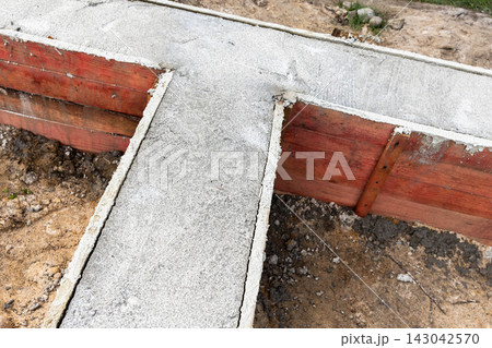 Concrete foundation footings poured into wooden formwork 143042570