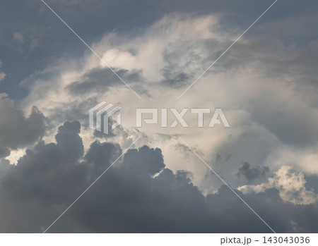 An extraordinary atmospheric display where nature elements mirror a grand canyon landscape. Deep, dark, jagged cloud banks form rugged "ridgelines" along the foreground, carving out a sweeping. 143043036